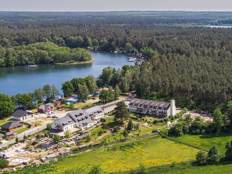 Blick auf die Gebäude des Hotels Gutenmorgen am See gelegen und umgeben von Wald