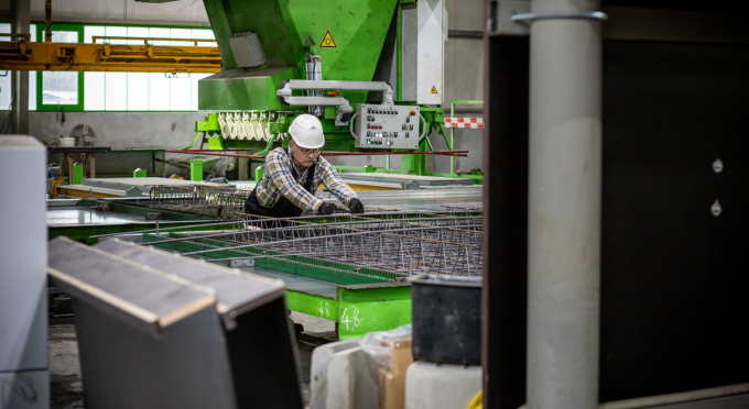 Männliche Person mit kariertem Hemd arbeitet an einer großen Metallarmierung in einer Industriehalle der MATTIG & LINDNER GmbH